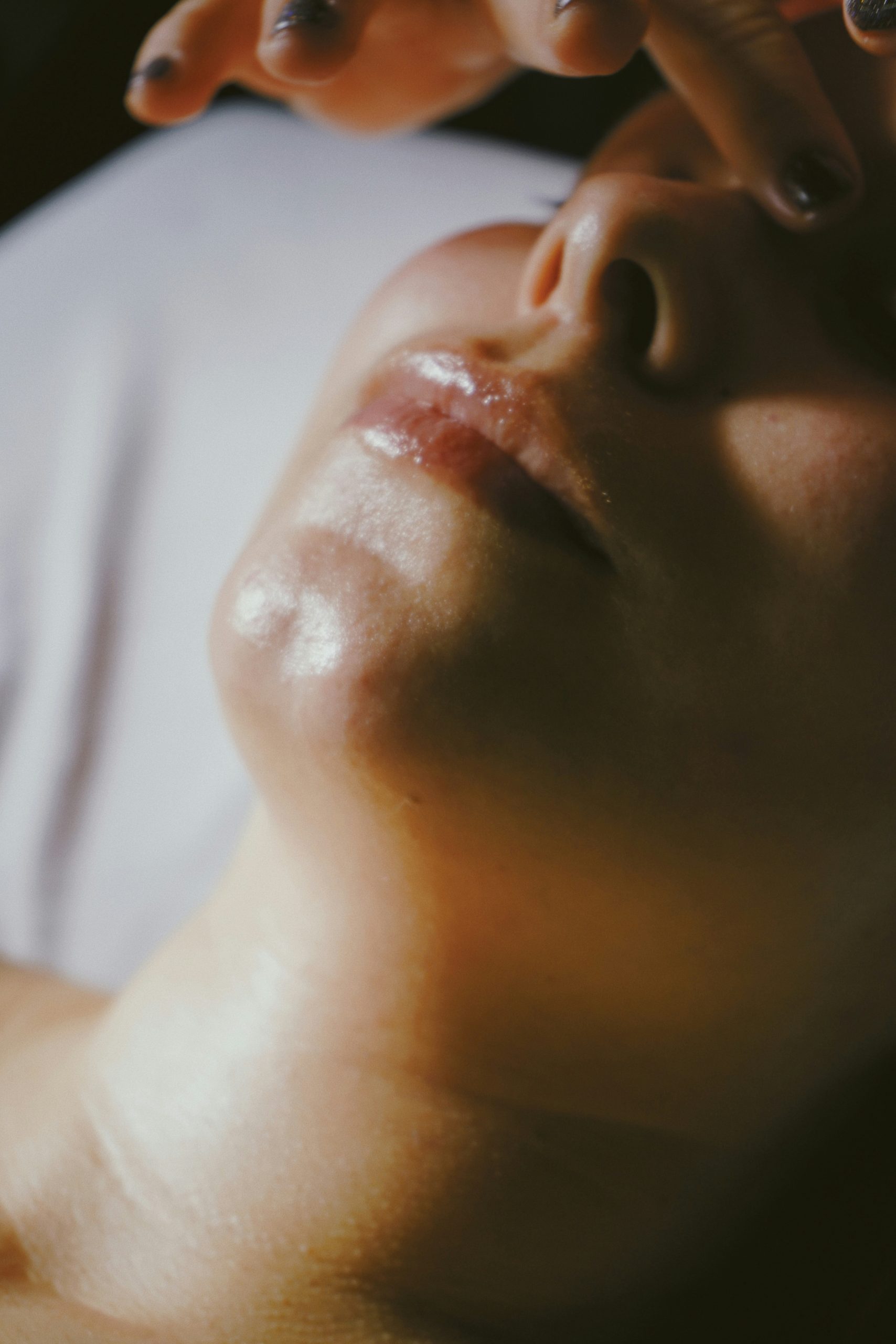 A dreamy image of a facial massage. A close up of a woman's face with hands about to touch her head.