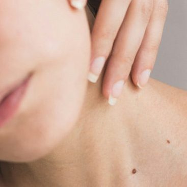 Close up of a woman's neck with a feminine hand resting gently on the skin.