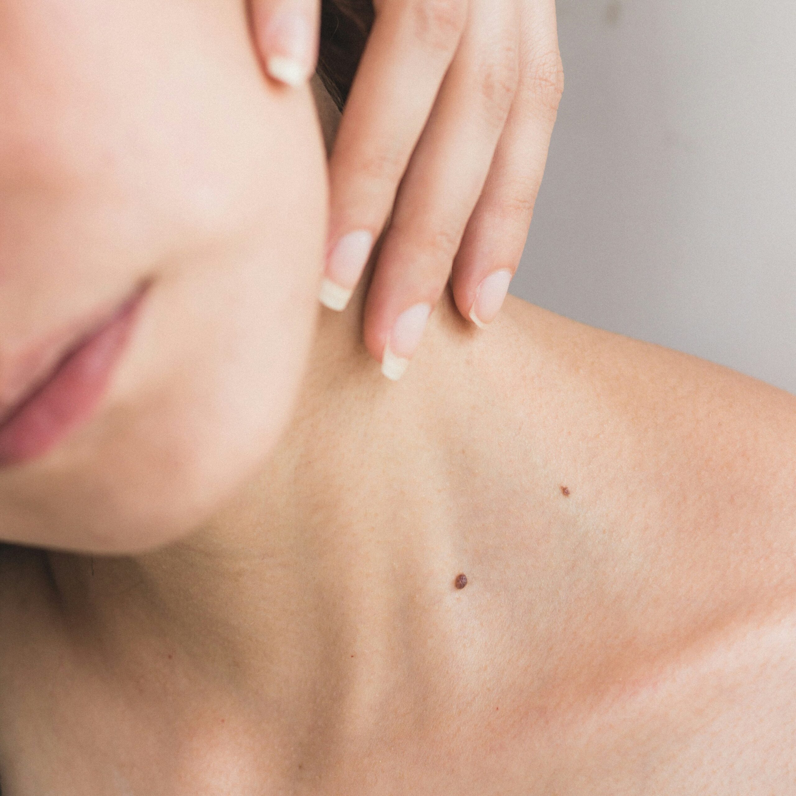 Close up of a woman's neck with a feminine hand resting gently on the skin.